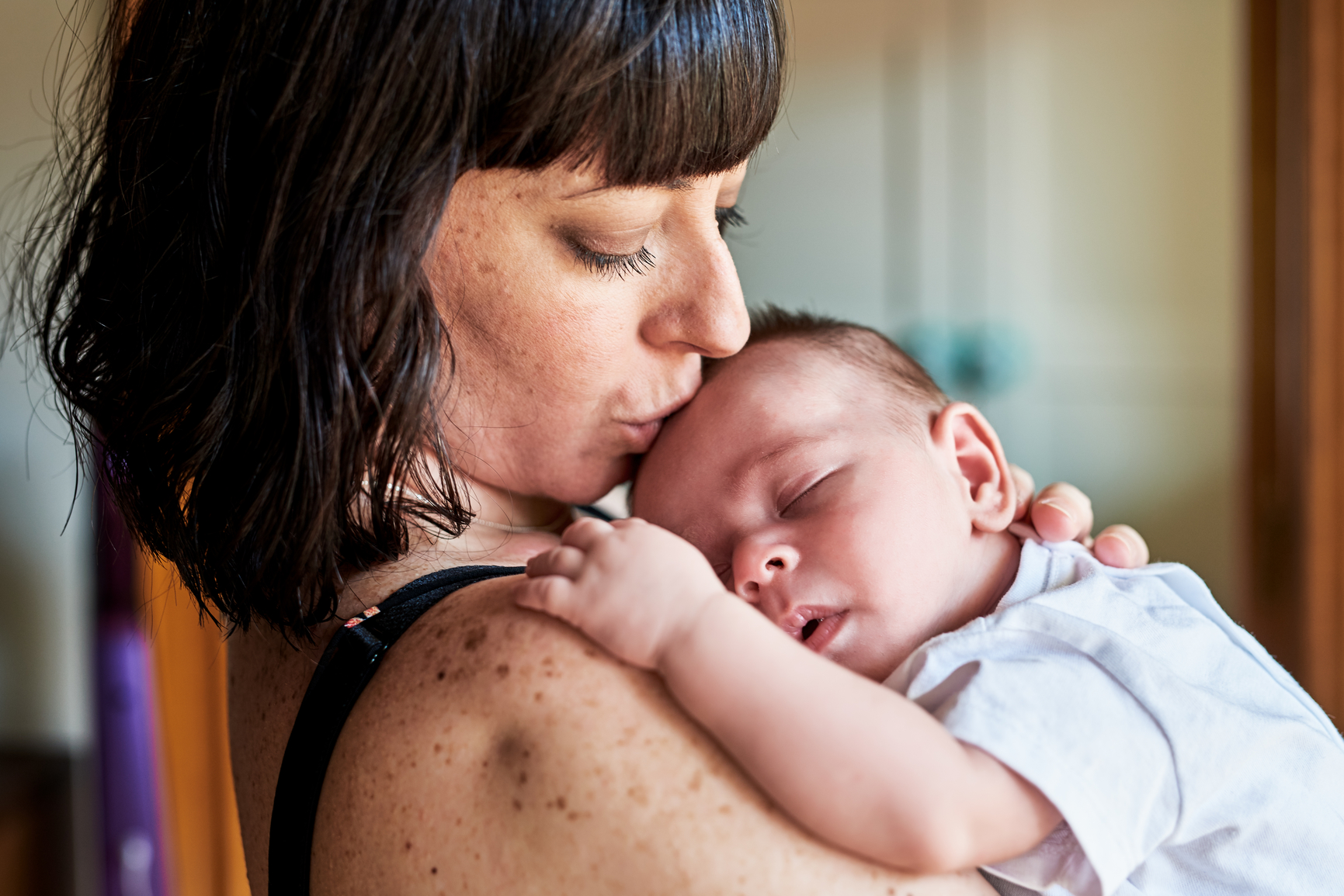Woman kissing sleeping baby on head