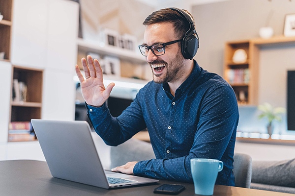 Young professional male waving to colleagues on a video call